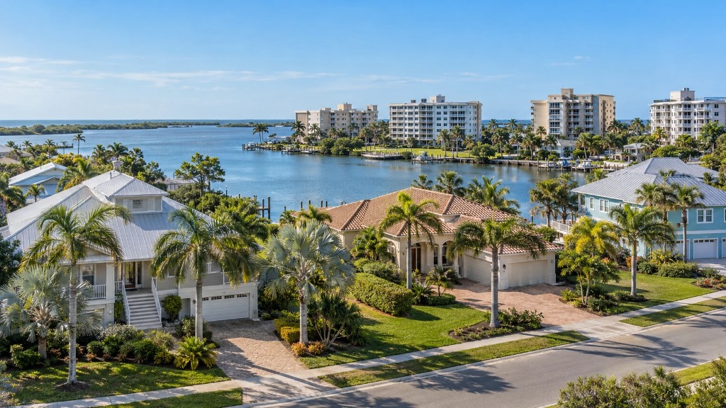 Aerial view of luxury waterfront homes and condominiums in a Florida coastal neighborhood under a clear blue sky.